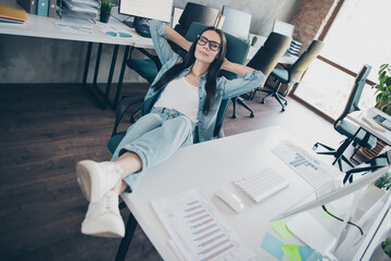 Wall Mural - Photo of attractive good mood lady recruiter dressed denim jacket smiling relaxing arms behind head indoors workplace workstation loft