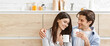 © Prostock-studio - A young couple is enjoying a cup of coffee together in a modern kitchen. The woman is looking at the man with a smile, while the man is looking at her with a loving expression, copy space