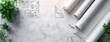 © Sudarshana - a wide angled horizontal flat lay closeup photo of an architectural blueprint drawings and drawing roles on a table
