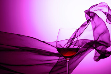 Wall Mural - Glass of red wine on a background of waving curtain.