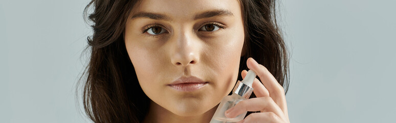 Wall Mural - A woman applies a clear serum to her face.