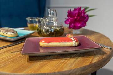 Wall Mural - A small red pastry sits on a purple plate on a wooden table