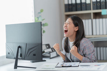 Sharing good business news. Attractive young businesswoman talking on the mobile phone and smiling while sitting at her working place in office and looking at laptop PC.