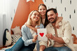 © Valerii Apetroaiei - A happy family in a cozy living room holding a heartshaped card, expressing love and togetherness