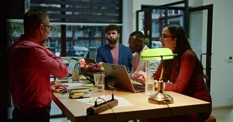 Wall Mural - In a well-lit contemporary office setting, a multi-ethnic team of four professionals collaboratively works around a table, illustrating the essence of teamwork in a diverse and modern workplace.