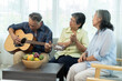 © pixs4u - Cheerful retired Asian friends Singing and Playing Guitar Together in living room