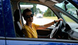 © Ekaterina - A young happy woman with a modern short haircut is sitting at the wheel of a car and smiling. The girl with sunglasses rented a car to go on a solo road trip in the summer.