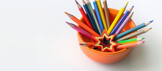 Wall Mural - A small orange bowl with colored pencils arranged in a star shape on a white surface, with copy space image.