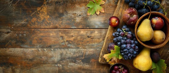 Wall Mural - Autumn-themed display featuring a variety of organic fruits like ripe grapes on a wooden cutting board, pears, and plums in bowls on a rustic wooden background with copy space image for text.