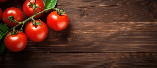 Sticker - Top view of fresh red tomatoes on a branch displayed on a dark brown wooden table with an oak texture, positioned on the left side, allowing for copy space image.