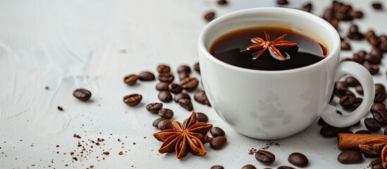 Wall Mural - A white cup filled with black aromatic coffee rests on a light table surrounded by roasted beans and an anise star, providing copy space in the image.