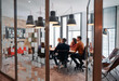 © .shock - In a sleek glass office space, a team of business professionals engage in lively discussions and exchange strategic ideas, showcasing collaboration and innovation at the heart of modern corporate
