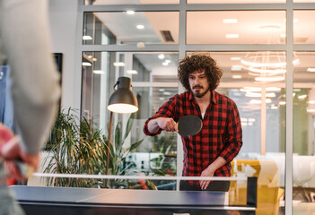 Wall Mural -  Business colleagues take a break from work to enjoy a game of table tennis, fostering teamwork and camaraderie in the workplace