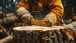 © Nano Photos - A person wearing protective gloves and clothing chops wood, with sawdust and wood shavings flying off from the chopping block.
