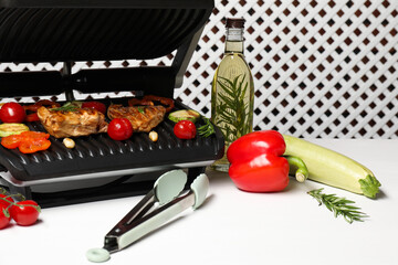 Wall Mural - Electric grill with different products and tongs on white table