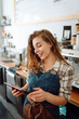 © maxbelchenko - Young woman owner with tablet stands behind the counter of a coffee shop. Business concept. Takeaway food.