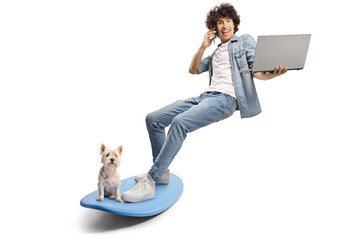 Sticker - Young man and a dog on a surfboard and using a smartphone and laptop computer