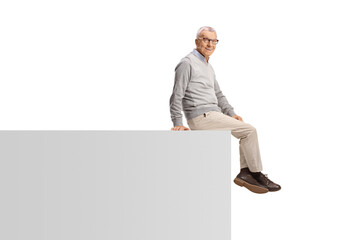 Wall Mural - Elderly man sitting on a wall