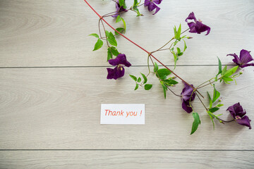 Wall Mural - branch of blooming purple clematis, on a light wooden table