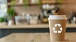 © May Chanikran - Eco-friendly disposable coffee cup with recycling symbol in modern coffee shop setting, promoting sustainability and environmental mindfulness.