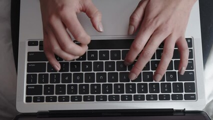 A person is typing on a laptop with their hands on the keyboard