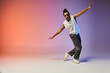 © LIGHTFIELD STUDIOS - A young African American man dances with style against a vibrant gradient backdrop.