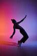 © LIGHTFIELD STUDIOS - A silhouette of a young African American man dancing against a gradient pink and purple background.