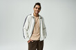 © LIGHTFIELD STUDIOS - A young African American man in a stylish white jacket poses against a grey background.
