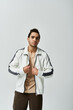 © LIGHTFIELD STUDIOS - A young African American man poses in a stylish white jacket against a grey background.