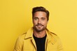 © Stocknterias - Smiling handsome man in yellow jacket looking at camera. Yellow background