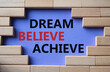 © Natallia - Dream Believe Achieve symbol. Concept words Dream Believe Achieve on wooden blocks. Beautiful purple background. Business and Dream Believe Achieve concept. Copy space