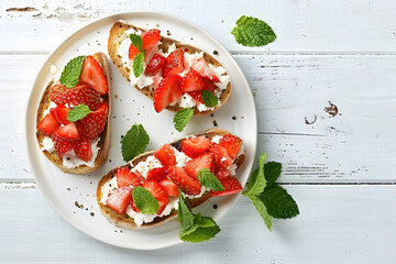 Wall Mural - Bruschettas with ricotta cheese, chopped strawberries and mint on white wooden table, top view