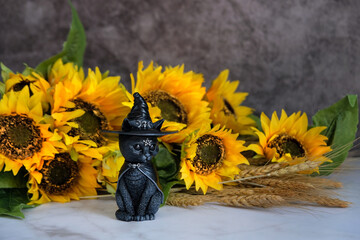 Poster - black cat figurine, sunflowers and wheat ears on table, abstract dark background. Wiccan altar for Mabon or Halloween, Samhain sabbat. Witchcraft, esoteric spiritual ritual.