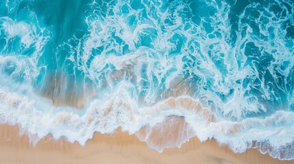 Wall Mural - A stunning aerial shot capturing turquoise ocean waves crashing onto a golden sandy beach, highlighting the dynamic beauty of the coastline under sunlight.