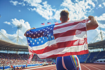 Wall Mural - American Runner Celebrates with USA Flag at Track Stadium. A young male athlete with light skin and short hair, joyfully holding the American flag, showcasing pride and achievement.
