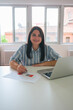 © ADDICTIVE STOCK - Smiling businesswoman working with laptop and documents