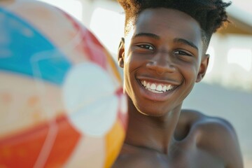 Wall Mural - A young boy with a bright smile and a beach ball is seen near the shore, enjoying his day with joy and carefree happiness on a sunny beach.