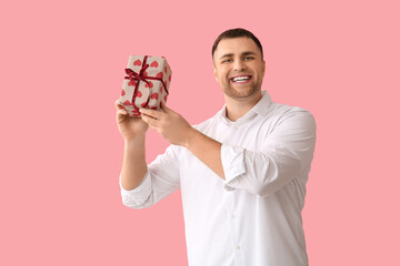 Wall Mural - Handsome young happy man with gift box on pink background