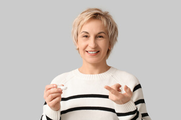 Poster - Mature woman with contact lens and case on grey background