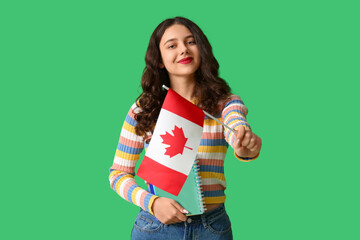 Canvas Print - Female student with notebook and flag of Canada on green background