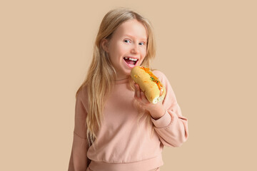 Canvas Print - Cute little girl eating tasty hot dog on color background