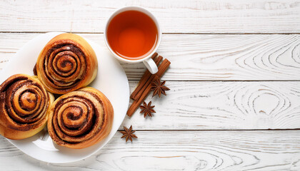 Canvas Print - A plate with delicious cinnamon rolls and a cup of tea on a white wooden table