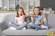 © Pixel-Shot - Cute little girls with sweet toasts sitting on sofa at home