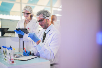 scientists perform experiments and record data. people arranges equipment with test tubes and chemicals for producing medicine and biochemistry. man hold tubes of chemical liquids and plant samples.