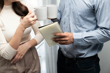 Wall Mural - Cropped horizontal view in drinking coworkers with coffee break together consulting business plan project in casual day at office. A man holding note paper to inform research presentation. Postulate.