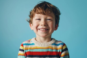 Sticker - Portrait of a smiling little boy in a striped sweater on blue background