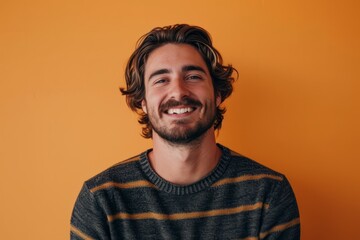 Wall Mural - Portrait of a handsome young man smiling and looking at camera against orange background