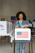 © Alan - vertical portrait of a young african american woman voting in the us election, placing vote ballot in the polling box, vote in America. Concept of usa choice, democracy and freedom
