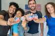 © Alan - diverse group of smiling friends holding 2024 Vote election I voted buttons or pins at a US election polling station. In the background, american flag at the background, democracy in America USA