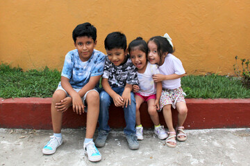 Wall Mural - Two happy and excited dark-skinned Latino boys and 2 girls celebrate Children's Day by playing and laughing